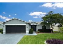 Charming single-story home featuring a well-manicured lawn, mature landscaping, and a two-car garage at 15825 Sw 11Th Court Rd, Ocala, FL 34473