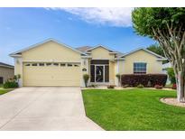 Charming yellow single-story home with a well-manicured lawn and attached two car garage at 1690 Sw 158Th Ln, Ocala, FL 34473