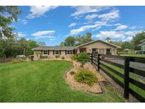Charming single-story home featuring a lush lawn, landscaping, and a stylish black wooden fence in a serene setting at 530 Sw 35Th St, Ocala, FL 34471