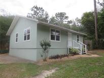 Charming home featuring a light green exterior, well-maintained landscaping, and a welcoming front porch at 5949 Se 164Th Ct, Ocklawaha, FL 32179