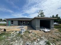Unfinished single-story home with a gray exterior, attached garage, and construction debris in the yard at 1057 Nw 68Th Pl, Ocala, FL 34474