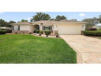 Charming single-story home featuring a well-manicured lawn, decorative stone driveway, and attached two-car garage at 13786 Se 88Th Ct, Summerfield, FL 34491