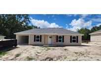 Charming home showcasing neutral siding, black shutters, new roof, and convenient attached carport at 24128 Sw South Lakes Ct, Dunnellon, FL 34431
