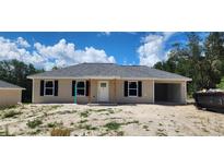 Charming single-story home featuring a welcoming front porch and an attached open garage at 24146 Sw South Lakes Ct, Dunnellon, FL 34431