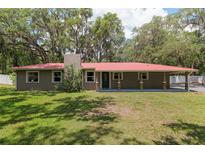 Charming ranch-style home with a red metal roof and mature trees in a private setting at 4010 Sw 7Th Avenue Rd, Ocala, FL 34471