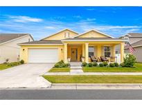 Charming yellow home with a welcoming front porch, well-manicured lawn, and an attached two-car garage at 7641 Sw 63Rd Lane Road, Ocala, FL 34474