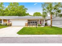 Charming home featuring a well-maintained lawn, a covered porch, and an attached garage at 8874 Sw 95Th St # E, Ocala, FL 34481