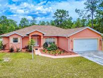 Charming one-story home with a lush, landscaped front yard and a two-car garage at 9325 Sw 125Th Court Rd, Dunnellon, FL 34432