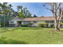 Ranch-style home with a sprawling green lawn, mature landscaping, and inviting front entrance at 2032 Se 12Th St, Ocala, FL 34471