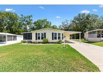 Charming single-story home featuring a lush lawn, carport, and screened entrance at 518 Saint Andrews Blvd, Lady Lake, FL 32159