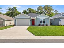 Charming single-story home with a well-manicured lawn, inviting red door, and attached garage at 6557 Se 4Th Ln, Ocala, FL 34472