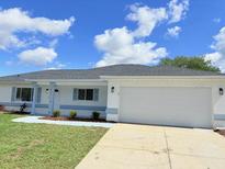 Charming single-story home featuring a two-car garage and well-maintained front lawn at 9029 Se 135Th Loop, Summerfield, FL 34491