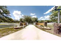 Long driveway leading to a gated home entrance with manicured landscaping and white fencing at 10528 Sw 27Th Ave, Ocala, FL 34476