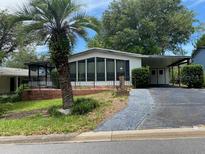 Charming single-story home featuring a palm tree, covered carport, and mature landscaping at 1408 Torrey Pines Dr, Lady Lake, FL 32159