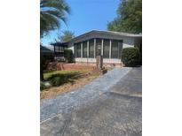 Inviting single-story home featuring a large windowed sunroom and well-maintained front yard at 1408 Torrey Pines Dr, Lady Lake, FL 32159