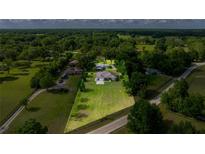 Expansive aerial view of a home surrounded by lush greenery and a well-maintained lawn at 465 Ne 155Th Street Rd, Citra, FL 32113