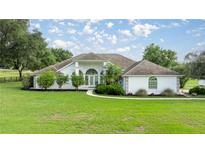 Charming single-story home with a pristine lawn, mature landscaping, and a welcoming entrance at 5661 Nw 96Th Ln, Ocala, FL 34482