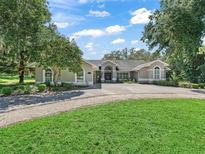 Charming single-story home featuring a circular driveway and mature trees in a lush, green yard at 5714 Nw 80Th Avenue Rd, Ocala, FL 34482