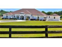 A charming single-story home with a well-manicured lawn and a quaint wooden fence at 6160 W Highway 326, Ocala, FL 34482