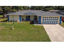 Charming single-story home with a well-maintained lawn, blue accents, and an attached two-car garage at 6211 Se 126Th St, Belleview, FL 34420