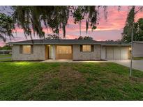 Charming single-story home with a stone facade, lush lawn and beautiful landscaping at sunset at 8463 Sw 108Th Ln, Ocala, FL 34481