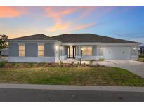 Charming single-story home with a well-manicured lawn, neutral paint, and welcoming front entrance at dusk at 10976 Sw 101St Loop, Ocala, FL 34481
