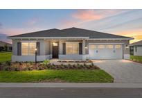 Charming single-story home featuring a well-manicured lawn and a two-car garage, illuminated by a picturesque sunset at 10977 Sw 101St Loop, Ocala, FL 34481