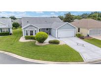 Charming single-story home with a well-manicured lawn, beautiful landscaping, and a two-car garage at 2608 Casso Ct, The Villages, FL 32162