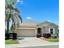Charming one-story home with well-manicured landscaping, brick driveway, and attached two-car garage in a sunny neighborhood at 5009 Neptune Cir, Oxford, FL 34484