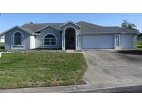 Charming single-story home with manicured lawn, inviting entryway, attached two car garage, and a long driveway at 5391 Nw 19Th Pl, Ocala, FL 34482