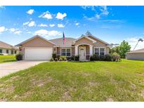 Charming single-story home featuring a well-manicured lawn, attached garage, and classic American flag at 10313 Sw 45Th Ave, Ocala, FL 34476