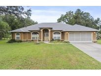 Charming single-story home featuring an arched entryway, well-maintained lawn, and attached two car garage at 10716 Sw 53Rd Cir, Ocala, FL 34476
