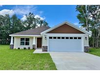 Charming single Gathering home featuring a two car garage, manicured lawn and stone veneer accents at 13303 Sw 106Th Pl, Dunnellon, FL 34432