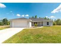 Charming single-story home with a well-maintained lawn and attached two-car garage on a sunny day at 13561 Sw 85Th Pl, Dunnellon, FL 34432