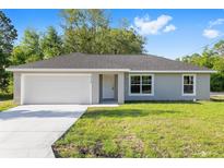 Charming single-story home with a two-car garage, well-maintained lawn, and inviting front entrance at 21301 Sw Rainbow Lakes Blvd, Dunnellon, FL 34431