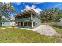 Two-story home featuring a screened-in porch, light green siding, and a gravel parking area at 24628 Fox Rd, Astor, FL 32102