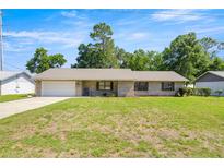 Charming single-story home features a brick facade, metal roof, and attached garage on a well-maintained lawn at 2981 Ne 39Th Pl, Ocala, FL 34479
