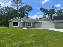 Charming single-story home featuring a well-manicured lawn and attached two-car garage at 4105 Se 138Th Pl, Summerfield, FL 34491