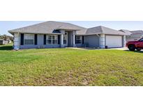 Charming single-story home featuring a well-maintained lawn, grey exterior paint, and a two-car garage at 5920 Sw 88Th Pl, Ocala, FL 34476