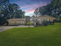 Charming single-story home with attached garage and lush green lawn at dusk at 11230 Se 47Th Ave, Belleview, FL 34420
