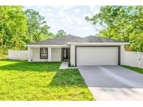 Charming single-story home with a well-maintained lawn, white fence, and a two-car garage at 13314 Se 41St Ct, Belleview, FL 34420