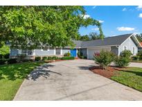 Charming one-story home with a large driveway, well-manicured lawn, blue front door, and tasteful landscaping at 1404 Se 40Th Ct, Ocala, FL 34471