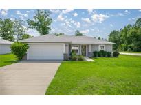 Charming single-story home with a well-manicured lawn, a two car garage and lovely landscaping at 16062 Se 89Th Ter, Summerfield, FL 34491