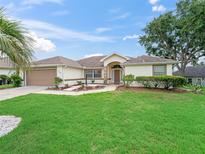Well-maintained single-story home featuring a landscaped front yard, two-car garage and mature shade trees at 17233 Se 115Th Terrace Rd, Summerfield, FL 34491
