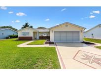 Charming single-story home featuring a manicured lawn, decorative driveway, and attached garage at 17576 Se 96Th Ct, Summerfield, FL 34491