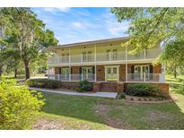 Charming two-story home with a brick facade, double balconies, and a well-manicured front lawn under a sunny sky at 20861 Sw 81St Loop, Dunnellon, FL 34431