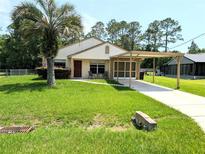 Charming single-story home with a well-maintained lawn, carport, and inviting front entrance at 21298 Sw Peach Blossom St, Dunnellon, FL 34431