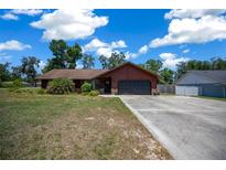 Charming single-story home with a well-manicured lawn and a long concrete driveway leading to an attached garage at 23 Larch Crse, Ocala, FL 34480