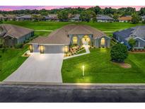 Beautiful home featuring a well-manicured lawn, arched windows, a three-car garage, and lovely landscaping at 2478 Nw 53Rd Avenue Rd, Ocala, FL 34482
