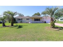 Charming single-story home featuring a well-manicured lawn and mature palm trees in the front yard at 6472 Sw 106Th Pl, Ocala, FL 34476
